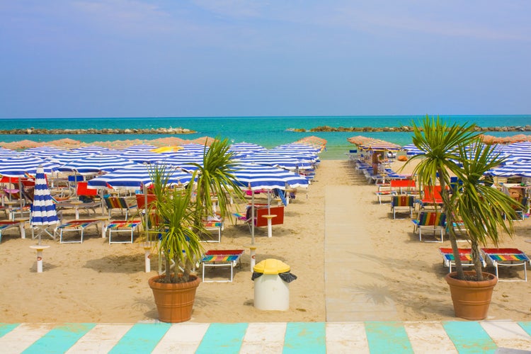 Beach with umbrellas and sun beds on coast in Pesaro, Italy