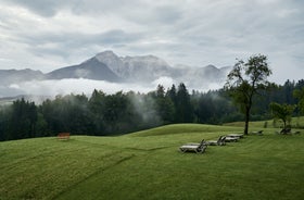 photo of Elevated, scenic view of the town of Bischofswiesen, Bavaria, Germany. The Watzmann Mountain, part of the Bavarian Alps rises into a majestic skyline. A green, spring landscape set in the valley.