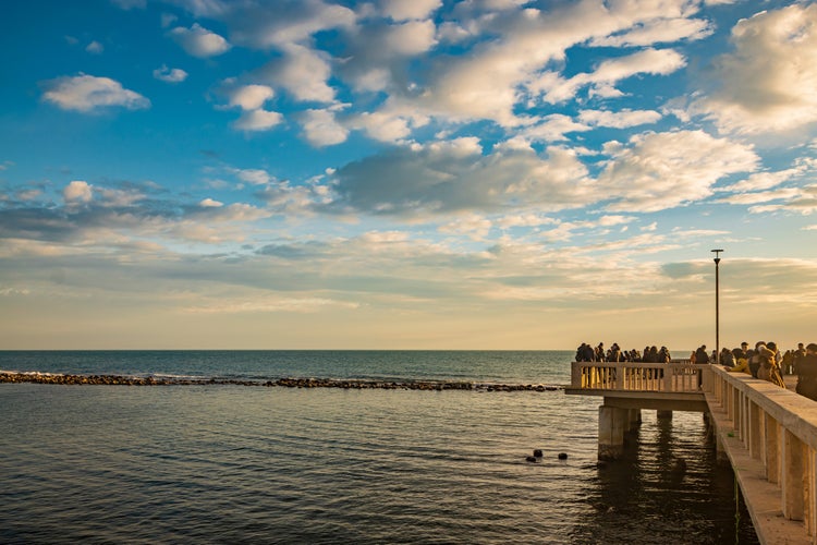 The sea of Ostia, on the Roman coast, on a winter Sunday. People enjoy the holiday walking on the pier in the open air in the evening.