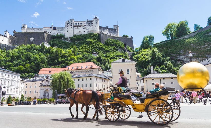 Photo of tourists sightseeing in horse carriage in Salzburg, Austria.