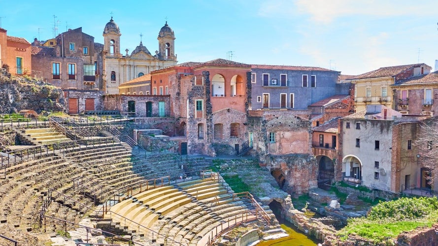 An ancient Roman theater surrounded by colorful historic buildings and a church, a highlight when exploring the best things to do in Catania..jpg