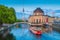 Beautiful view of UNESCO World Heritage Site Museumsinsel (Museum Island) with excursion boat on Spree river and famous TV tower in the background in beautiful evening light at sunset, Berlin.