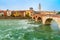 photo of Ancient Roman bridge Ponte Pietra and the River Adige in cloudy summer day, Duomo tower in background, Verona, Italy .