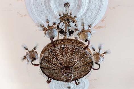 Old style vintage brass crystal chandelier in Niko Berdzenishvili Kutaisi State History Museum, main exhibition room, gypsum ornaments on the ceiling.