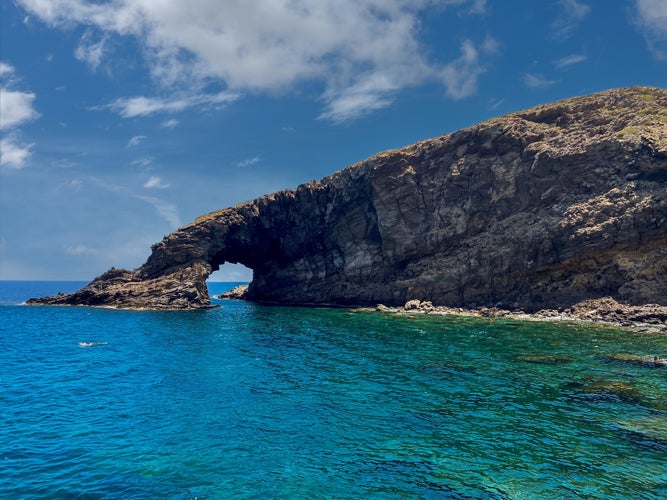 photo of Elephant Arch huge lava rock cliff plunging into the water forming an arch is the symbol of the island of Pantelleria, Sicily, Italy.