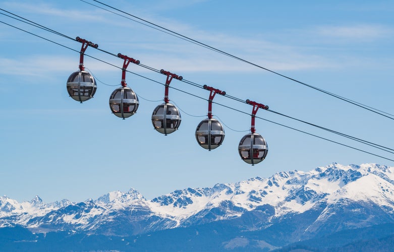 Gondola bubbles against the blue sky and the French Alps in the background. Cable car taking tourists to Fort de La Bastille in Grenoble, France