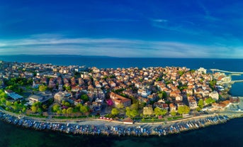 Photo of Saint Anastasia Island in Burgas bay, Black Sea, Bulgaria. Lighthouse tower and old wooden buildings on rocky coast.