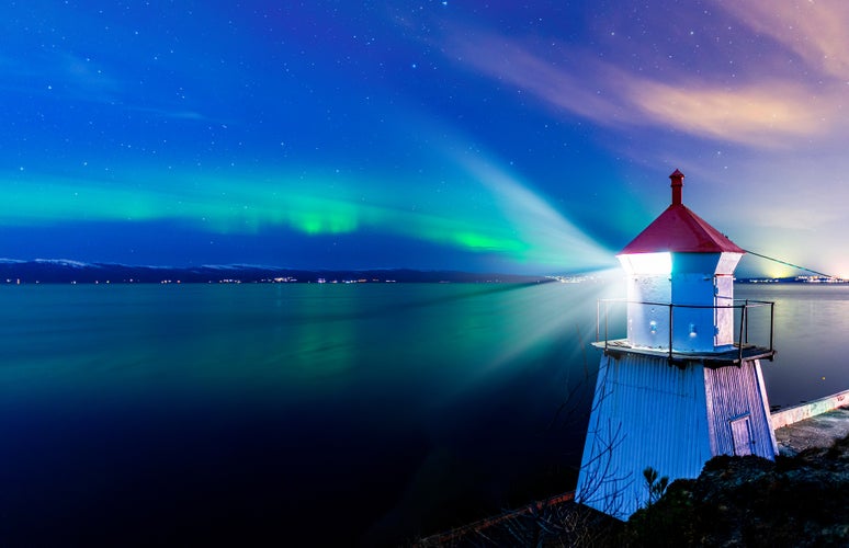 A light house in Trondheim with a sky with northern lights in the background.