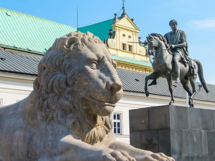 Stone statue of a lion and monument to Prince Jozef Poniatowski near Presidential Palace, Warsaw, Poland