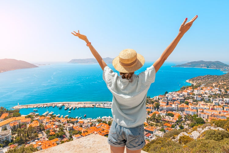 Happy woman with open arms stands on the viewpoint and enjoys the panorama of Kas.