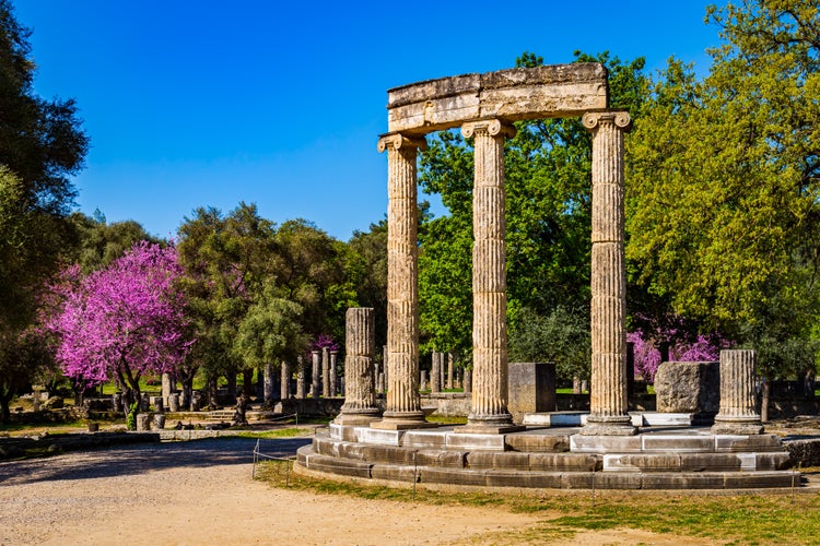 Photo of The ruins of Ancient Olympia with blooming cercis tree. Greece.