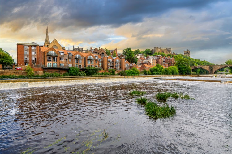 photo of view of The skyline of the city of Durham including the Romanesque Durham Cathedral and Durham Castlen, now a university, is seen behind the River Wear under a dramatic sky in Durham, England UK.