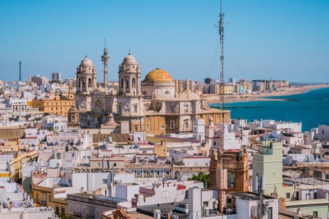 photo of rooftops of houses in aerial view of the medieval city of Cádiz and towers and Cathedral Cádiz in seafront, Spain.