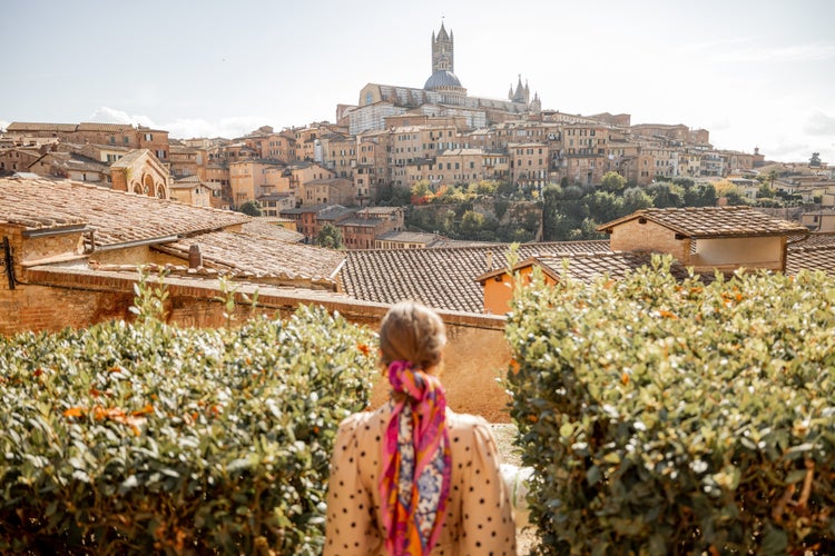 photo of view of Stylish woman walks on background of cityscape of Siena old town. Concept of travel famous cities in Tosacny region of Italy