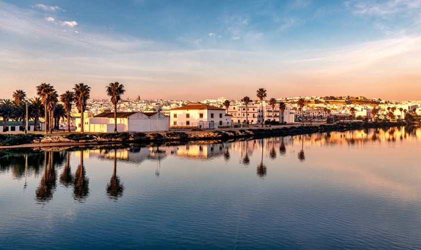 Photo of panoramic beautiful view of Conil de la Frontera in southern Spain at sunset, and town reflections on the calm waters.