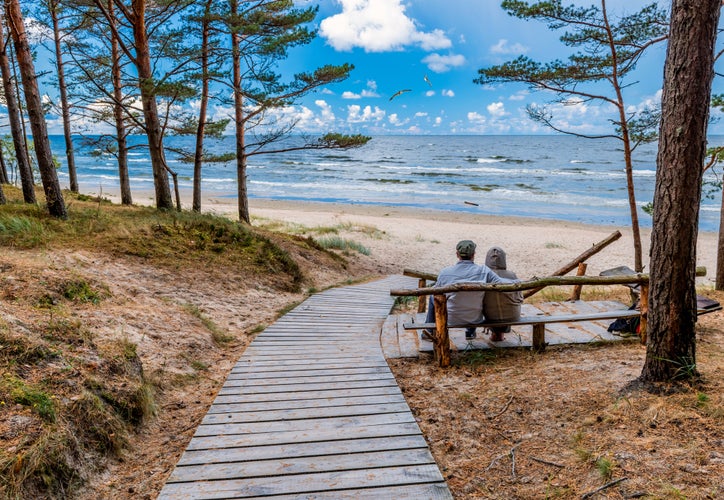 Coastal landscape with resting place among pine forest and wooden footpath leading to sandy beach of the Baltic Sea, Jurmala, Latvia