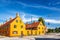 Photo of old yellow houses of Nyboder district and woman on a bicycle during summer sunny day. Old Medieval district in Copenhagen, Denmark.