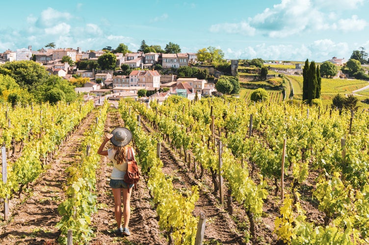 Photo of woman enjoying Saint Emilion village in green vineyard, Bordeaux in France.