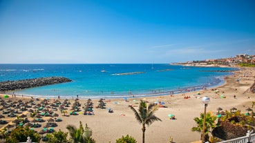 photo of aerial shot of Costa Adeje area, South Tenerife, Spain. Captured at golden hour, warm and vivid sunset colors. Luxury hotels, villas and restaurants behind the beach.