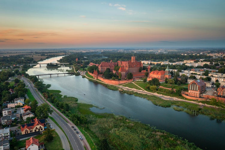 photo of view ofThe Castle of the Teutonic Order in Malbork by the Nogat river at sunset. Poland.