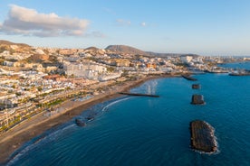 photo of aerial shot of Costa Adeje area, South Tenerife, Spain. Captured at golden hour, warm and vivid sunset colors. Luxury hotels, villas and restaurants behind the beach.