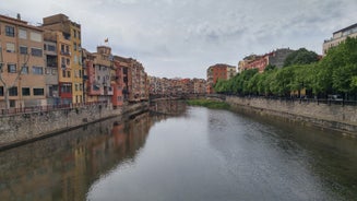 Photo of colorful yellow and orange houses and Eiffel Bridge, Old fish stalls, reflected in water river Onyar, in Girona, Catalonia, Spain.