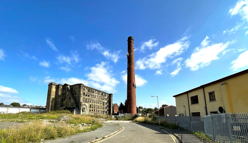 Tall Victorian red brick chimney, next to an old derelict mill, in the post industrial city of, Bradford, Yorkshire, UK