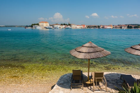 Photo of Beach and resort with beach chairs and umbrellas in morning light on the beach of a Croatian seaside holiday resort in Porec.