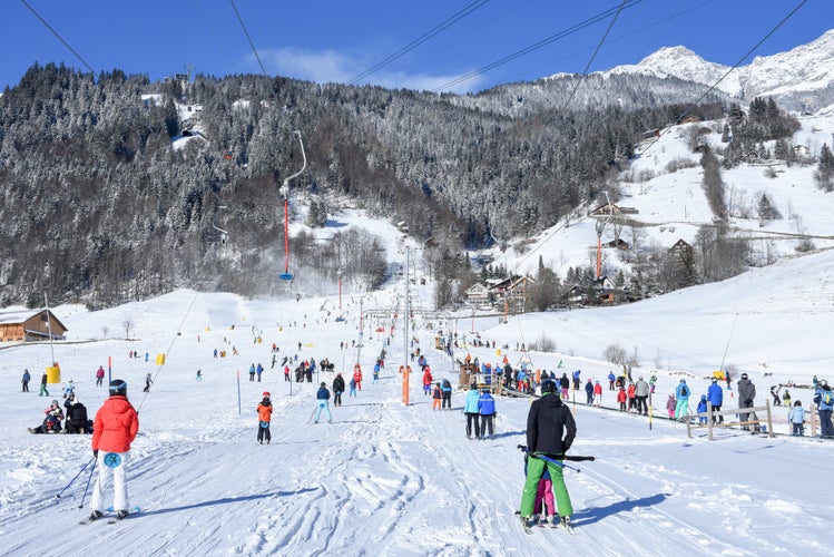 people going up with the ski lift and skiing down the slope of Engelberg in the Swiss Alps.