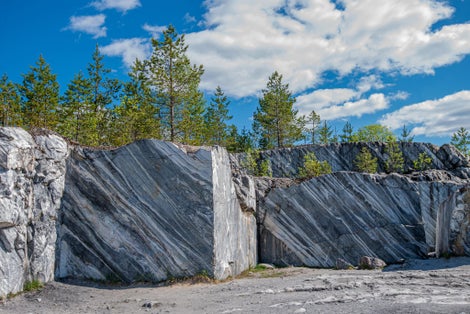 photo of Large grey stones in an old abandoned quarry. Marble texture. Smooth cuts on the rocks. The marble quarry is horizontal. The natural stone. Marble quarry, marble rocks in the wild.