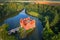 Photo of aerial view of bizarre water castle Cervena Lhota, red château standing at the middle of a lake on a rocky island, Czech Republic.