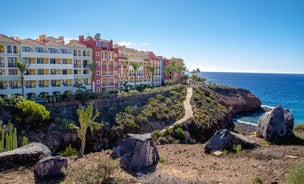 photo of aerial shot of Costa Adeje area, South Tenerife, Spain. Captured at golden hour, warm and vivid sunset colors. Luxury hotels, villas and restaurants behind the beach.