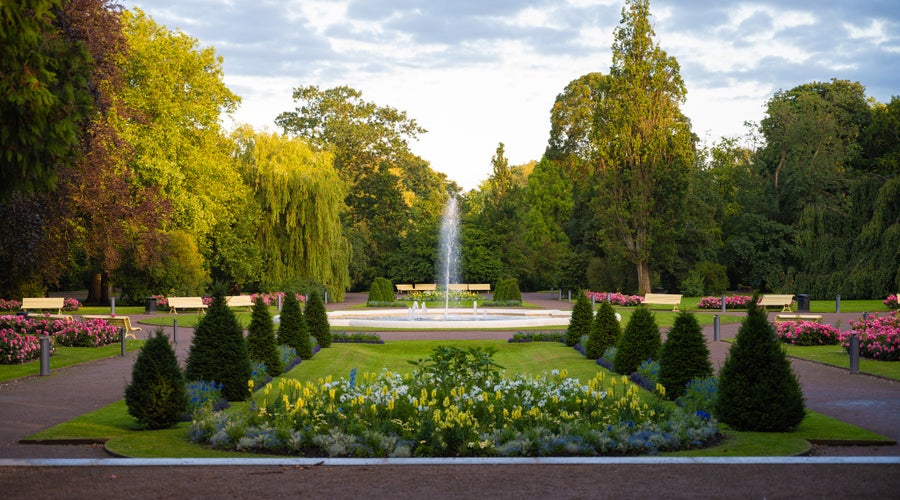 photo of flower arrangements in symetrical shapes leading up to a fountain in the city park Stadsparken in the town Lund, Sweden.