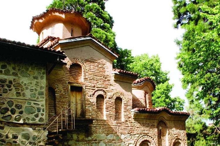 Boyana Church, a medieval Bulgarian Orthodox church with intricate brick architecture, arched windows, and a dome, surrounded by tall trees..jpg