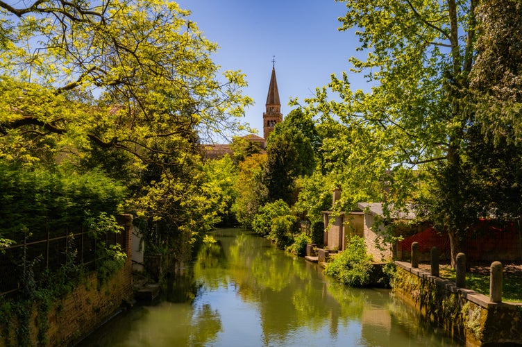 Photo of view over a beautiful green part of the old town of Portogruaro along the Lemene river, revealing kind of a garden city.