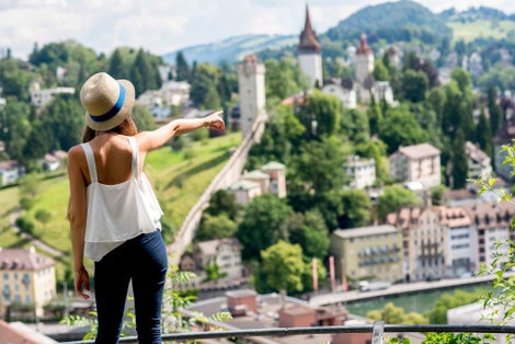 photo of young female traveler enjoying great view on Lucerne cityscape with the Männliturm tower in Switzerland.