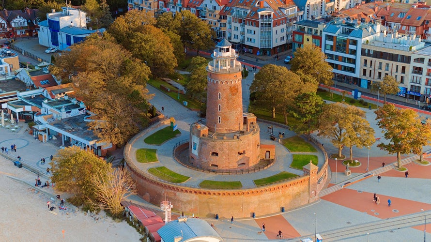 This aerial shot focuses on Kołobrzeg's iconic lighthouse and the thriving harbor beneath it. The coastal charm, combined with the maritime atmosphere of this Polish gem, is beautifully showcased.