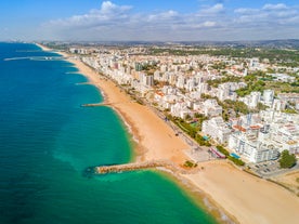 Photo of wide sandy beach in white city of Albufeira, Algarve, Portugal.