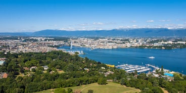 Geneva skyline cityscape, French-Swiss in Switzerland. Aerial view of Jet d'eau fountain, Lake Leman, bay and harbor from the bell tower of Saint-Pierre Cathedral. Sunny day blue sky.