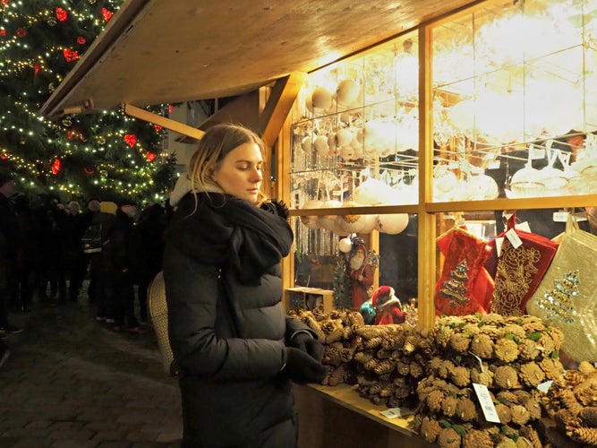 Winter holiday shopping in Bruges, a girl buys Christmas decorations at a city fair.jpg