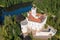 Photo of aerial view of Trakoscan castle surrounded by the lake and forested hills, rural Croatia.