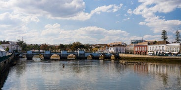 Photo of aerial cityscape of beautiful Tavira with roman bridge over Gilao river in the evening, Algarve, Portugal.