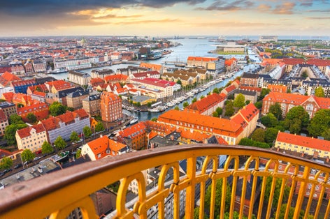 Photo of skyline of Copenhagen from external winding staircase to the top of church of Vor Frelsers Kirke during sunset, Copenhagen, Denmark.