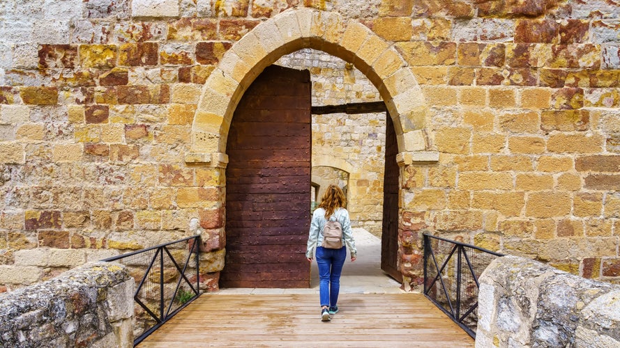 photo of view of Woman entering through the medieval gate of the old castle of Zamora Spain.