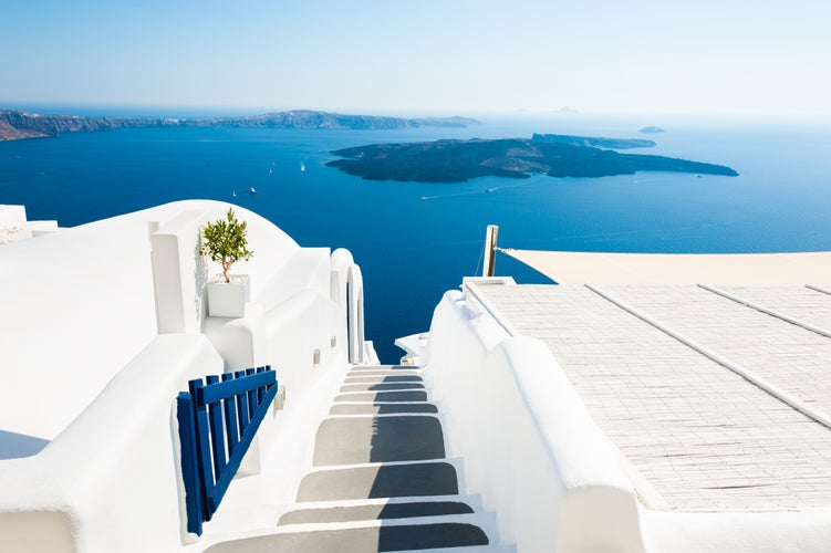 Photo of traditional narrow street with stairs leading to the beach in Oia village, Santorini Island, Greece.