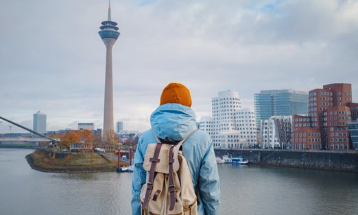 photo of view  of  autumn or winter travel to Dusseldorf, Germany. young Asian tourist or student in blue jacket and yellow hat ( symbol of Ukraine) walks through sights of European city. beautiful view in the Media Bay