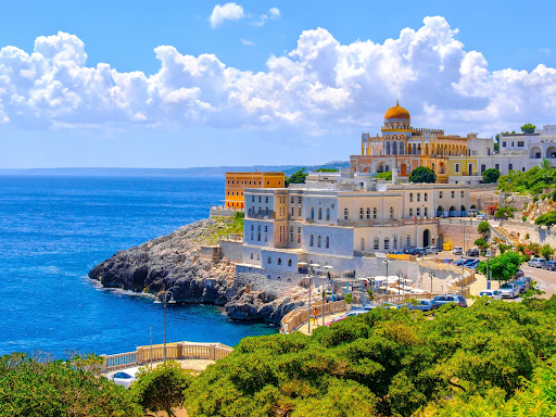 Scenic view of Santa Cesarea Terme, Italy, with coastal cliffs, historic buildings, and the Ionian Sea..png
