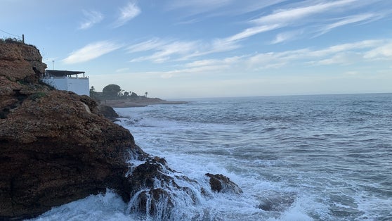 photo of view of Captured in Las Rotas, Spain, amidst turbulent weather and high waves on an evening with a sunset glow. Evoking a romantic atmosphere in the midst of nature's drama.