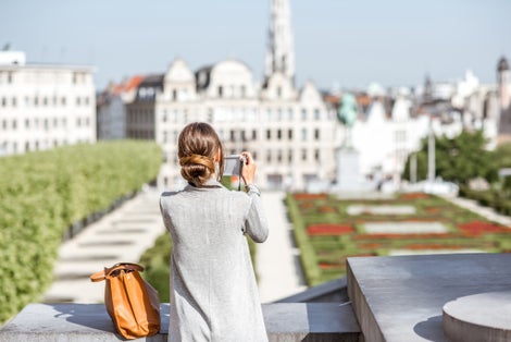Photo of female traveler standing with photocamera on the famous Arts mountain with great view on the old city in Brussels