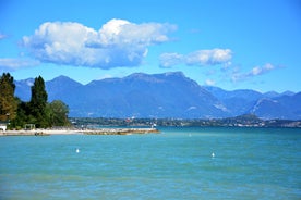 Photo of Old harbour Porto Vecchio with motor boats on turquoise water, green trees and traditional buildings in historical centre of Desenzano del Garda town, Northern Italy.